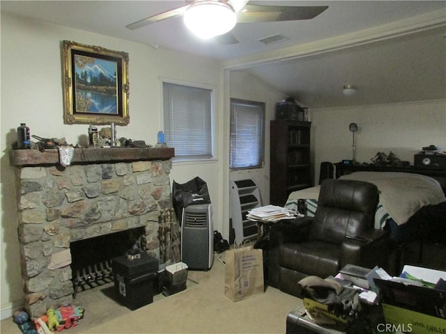 carpeted living room featuring ceiling fan, a stone fireplace, and lofted ceiling