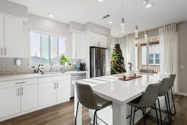 kitchen featuring white cabinetry, stainless steel appliances, tasteful backsplash, a kitchen island, and sink