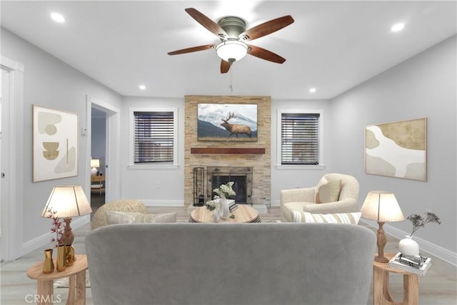 living room featuring ceiling fan, a fireplace, and light wood-type flooring