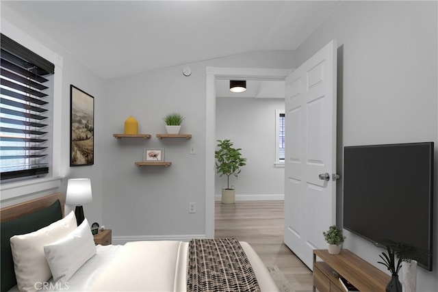 bedroom featuring multiple windows, lofted ceiling, and light hardwood / wood-style floors