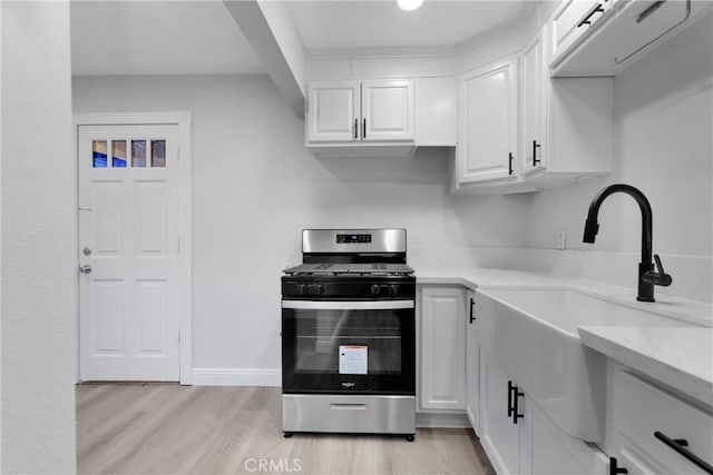 kitchen featuring white cabinetry, sink, light wood-type flooring, and stainless steel gas stove