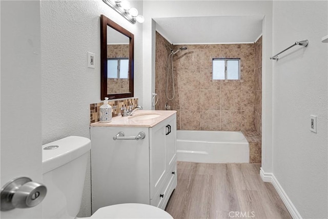 full bathroom featuring vanity, tiled shower / bath combo, wood-type flooring, and toilet