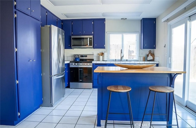 kitchen featuring blue cabinetry, a kitchen breakfast bar, a healthy amount of sunlight, and stainless steel appliances