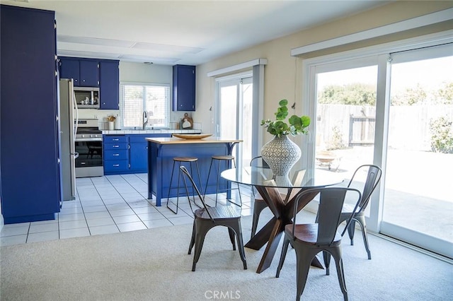 dining area with sink, light colored carpet, and a healthy amount of sunlight