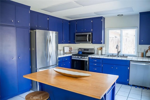 kitchen with sink, blue cabinets, and appliances with stainless steel finishes