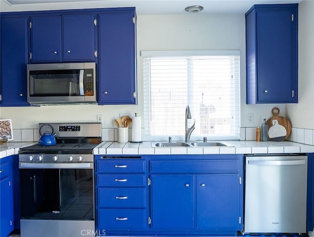 kitchen with tile countertops, sink, blue cabinets, and stainless steel appliances