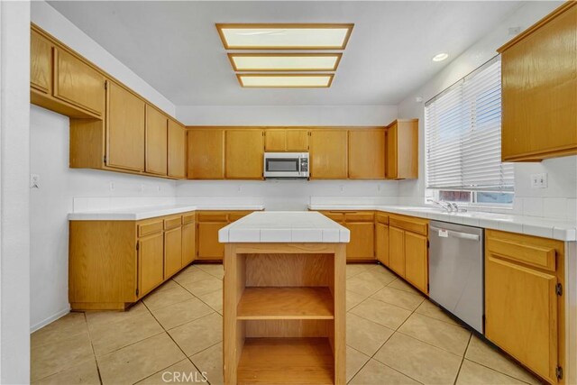 kitchen featuring tile countertops, a center island, light tile patterned floors, and stainless steel appliances