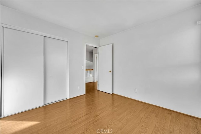 unfurnished bedroom featuring light wood-type flooring and a closet