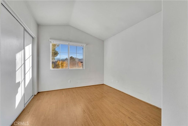 unfurnished room with vaulted ceiling and light wood-type flooring