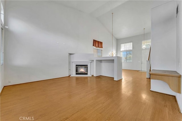 unfurnished living room featuring high vaulted ceiling and wood-type flooring