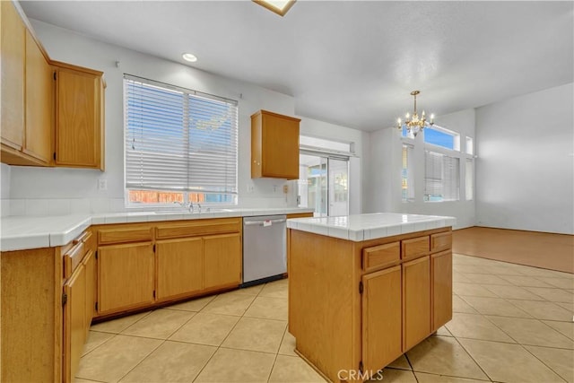 kitchen featuring stainless steel dishwasher, a chandelier, a kitchen island, tile counters, and light tile patterned flooring