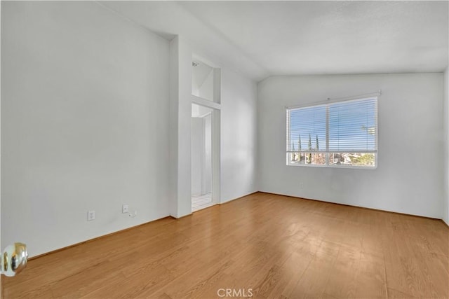 empty room with light hardwood / wood-style flooring and lofted ceiling