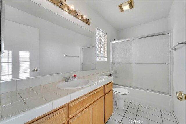 full bathroom featuring tile patterned floors, vanity, toilet, and shower / bath combination with glass door