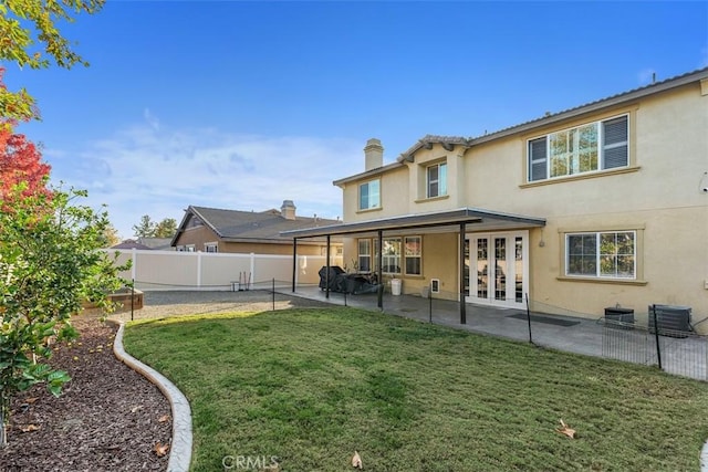 rear view of house with french doors, a patio, and a lawn