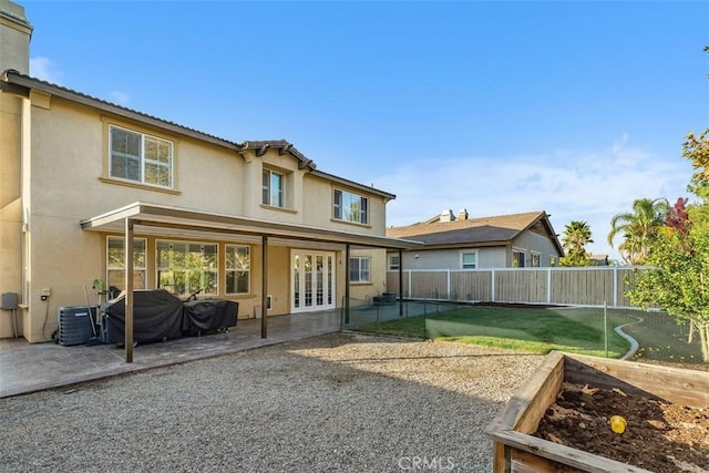 rear view of property featuring a lawn, central air condition unit, french doors, and a patio