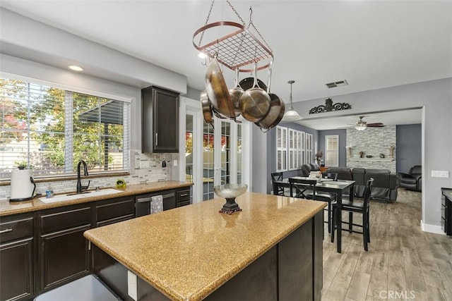 kitchen with dark brown cabinetry, ceiling fan, sink, backsplash, and light hardwood / wood-style floors