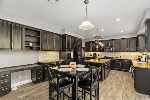 kitchen featuring pendant lighting, light wood-type flooring, appliances with stainless steel finishes, tasteful backsplash, and dark brown cabinetry