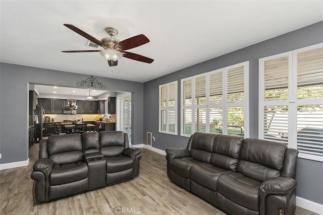 living room with light wood-type flooring and ceiling fan