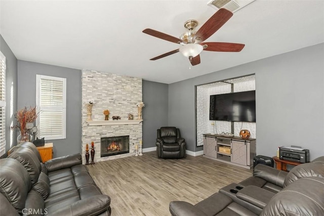 living room featuring ceiling fan, a fireplace, and light hardwood / wood-style flooring