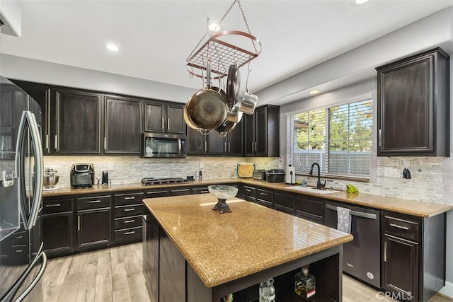 kitchen with sink, light hardwood / wood-style floors, dark brown cabinets, a kitchen island, and appliances with stainless steel finishes