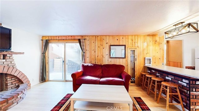 living room featuring wood walls, a fireplace, and light hardwood / wood-style floors