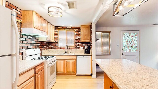 kitchen with visible vents, light wood finished floors, white appliances, under cabinet range hood, and a sink