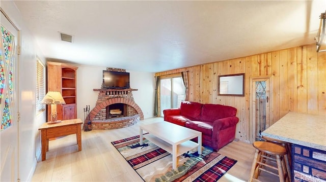 living room featuring a fireplace, light wood-type flooring, and wooden walls