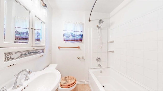 full bathroom featuring tiled shower / bath combo, toilet, and sink