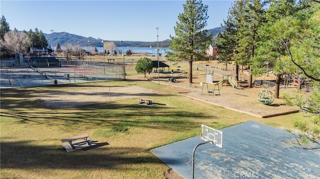 view of home's community featuring a lawn, a water and mountain view, and tennis court