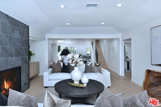 living room with lofted ceiling, light wood-type flooring, and a fireplace