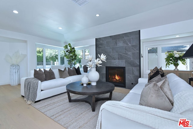 living room featuring a tile fireplace and light hardwood / wood-style floors