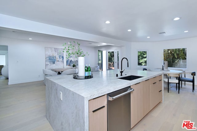 kitchen with dishwasher, sink, light brown cabinets, an island with sink, and light wood-type flooring