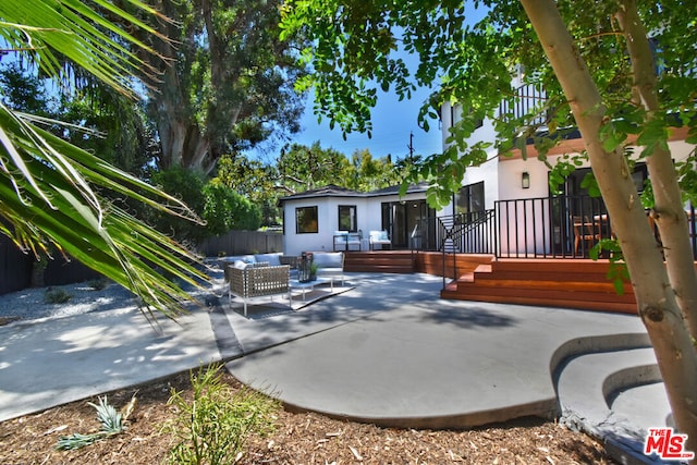 back of property featuring an outdoor living space, a patio, and a wooden deck