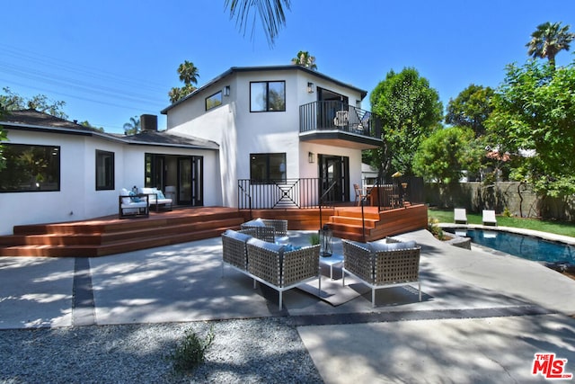 back of house with a swimming pool side deck, an outdoor living space, a balcony, and a patio area