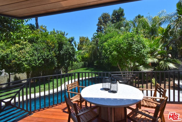 wooden terrace featuring a fenced in pool and a lawn