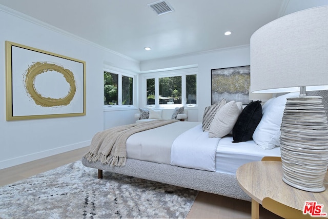 bedroom featuring ornamental molding and light hardwood / wood-style flooring