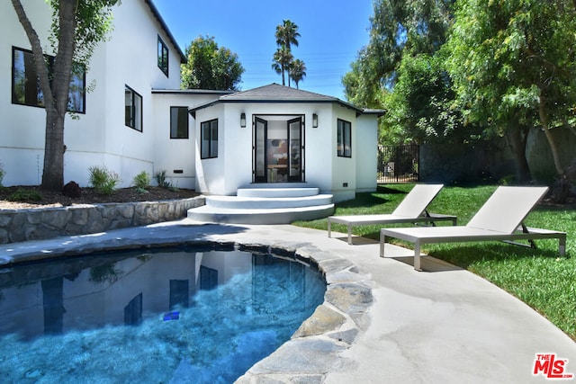 rear view of property featuring a fenced in pool and a patio area