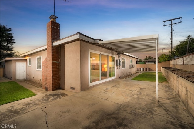 back house at dusk featuring a storage shed and a patio