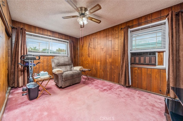 sitting room with a textured ceiling, light colored carpet, ceiling fan, and wood walls