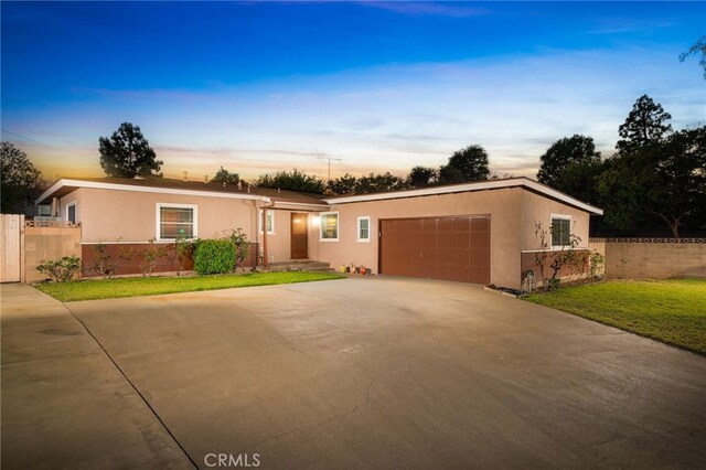 single story home featuring a garage and a yard