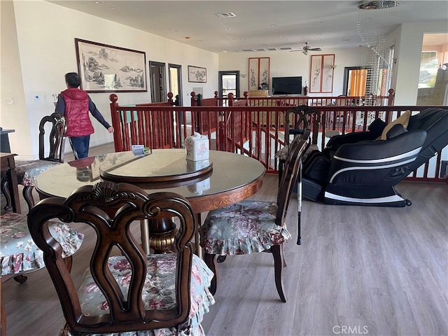 dining room with ceiling fan with notable chandelier and wood-type flooring