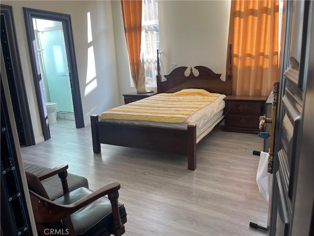 bedroom featuring connected bathroom and light hardwood / wood-style flooring