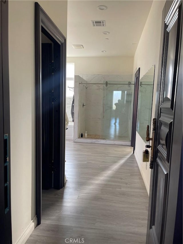 bathroom with wood-type flooring and a shower with door