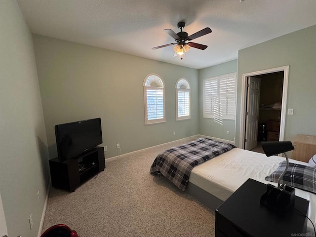 carpeted bedroom featuring ceiling fan and a spacious closet