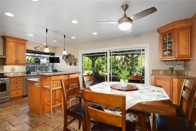 kitchen with ceiling fan, light stone countertops, stainless steel appliances, and hanging light fixtures