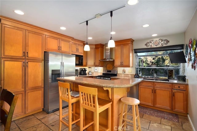 kitchen with a center island, wall chimney exhaust hood, decorative light fixtures, a breakfast bar area, and appliances with stainless steel finishes