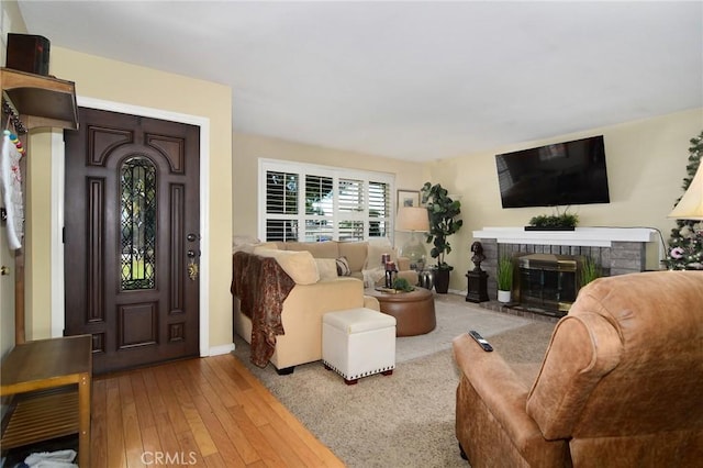 living room with wood-type flooring and a brick fireplace