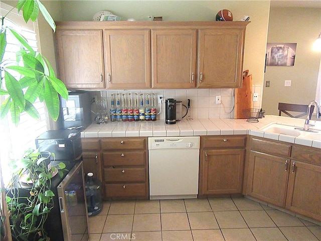 kitchen featuring tile counters, dishwasher, plenty of natural light, and sink