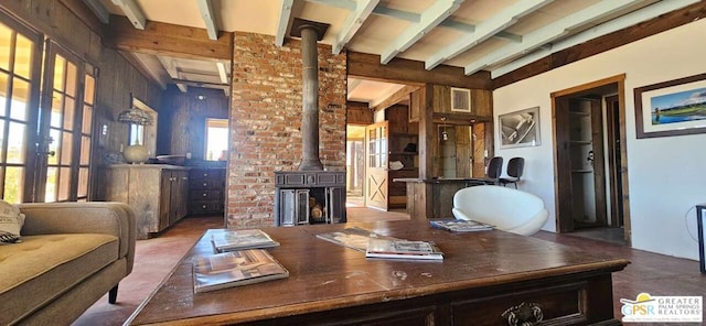 office featuring beam ceiling, a wood stove, and wood walls