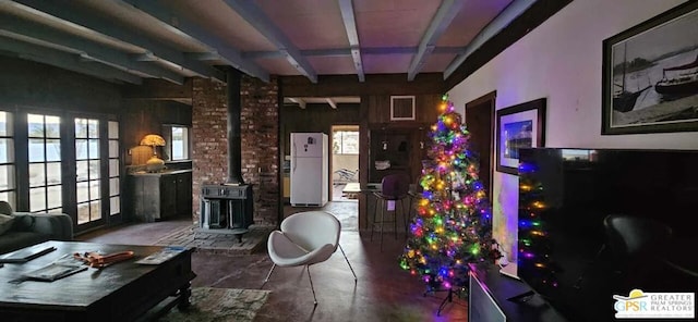 interior space featuring beamed ceiling, french doors, a wood stove, and wooden walls